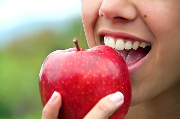 Biting an apple Closeup of a mouth biting a red apple biting stock pictures, royalty-free photos & images