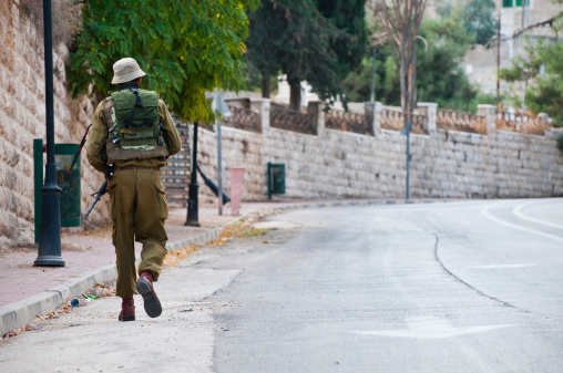 Hebron, Israel - October 21, 2010:An Israeli soldier on foot patrol  on Shuhada Street in the Palestinian city of Hebron. In most of the Palestinian Territories, Jewish settlers live outside major Palestinian population centers. Hebron is the exception, with several hundred settlers living in the center of a city of 165,000 Palestinians. The Israeli army guards these settlers and restricts Palestinian movement around the settlements, including on this empty street. Hebron is home to the Tomb of the Patriarchs.