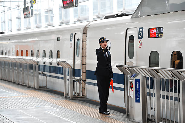 Kyoto, Japan - November,8 2010: Japanese female station master giving a sign to the train conductor for departure of the high speed bullet train (Shinkansen)  at the Kyoto Station.
