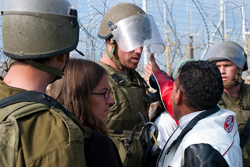 Bilin, West Bank - December 8, 2006: A Palestinian resident of the West Bank village of Bilin argues with Israeli soldiers guarding the separation barrier that has separated many in the village from their agricultural fields. Moments later he was arrested. The woman is probably an Israeli activist opposed to the barrier; Israeli and international activist join with Palestinians each Friday to protest the barrier.