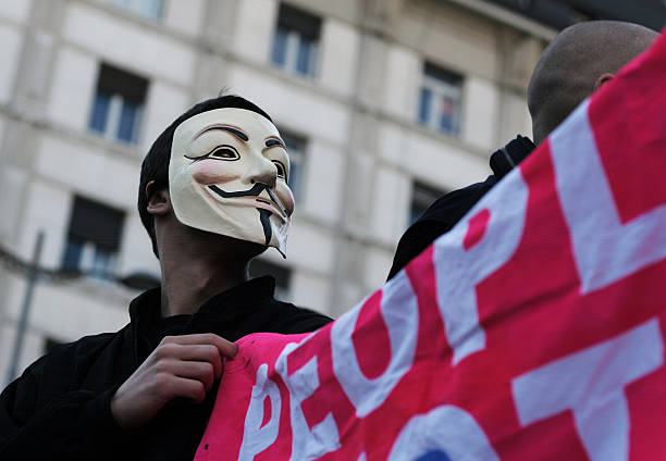 uomo con maschera tenendo banner anonimo, - anonymous rete di attivisti foto e immagini stock