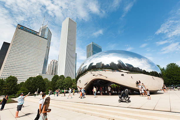 The Bean at Millennium Park in Front of Downtown Chicago "Chicago, USA - Jul 24, 2012: Park visitors and tourists gathered at ""Cloud Gate"", a modern sculpture created by Anish Kapoor, one of the many attractions at the Millennium Park in Chicago." millennium park stock pictures, royalty-free photos & images