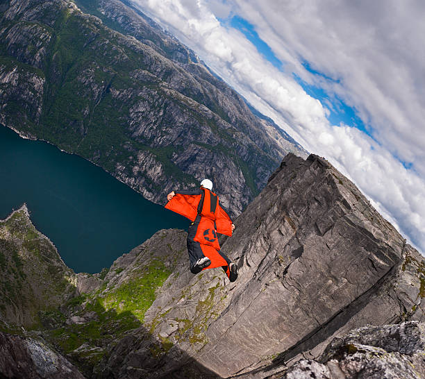 Wingsuit B.A.S.E. jumper jumps off a cliff at Kjerag, Norway. "Kjerag, Norway - August 21, 2010: a BASE jumper in wingsuit  jumps off a cliff at Kjerag plateau, Norway. Wingsuit cliff jumping and terrain flying are advanced BASE jumping disciplines that make human flight possible." ryfylke stock pictures, royalty-free photos & images