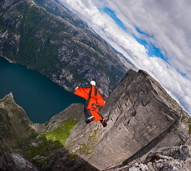 wingsuit b.a.s.e. jumper saltos em um penhasco no kjerag, noruega. - rock norway courage mountain - fotografias e filmes do acervo