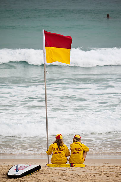 Lifeguards on Bondi Beach Sydney, Australia - April 8th, 2012: Two female lifeguards in their yellow and red uniforms on Bondi Beach. red yellow flag beach stock pictures, royalty-free photos & images