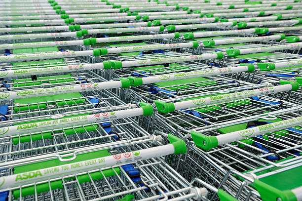 Asda Shopping Trolleys "Birmingham, England - February 14, 2011: Asda shopping trolleys lined up outside supermarket. Asda is a British supermarket chain which retails food, clothing, toys and general merchandise. Asda became a subsidiary of the American retail giant Wal-Mart, the worldaas largest retailer in 1999." asda photos stock pictures, royalty-free photos & images