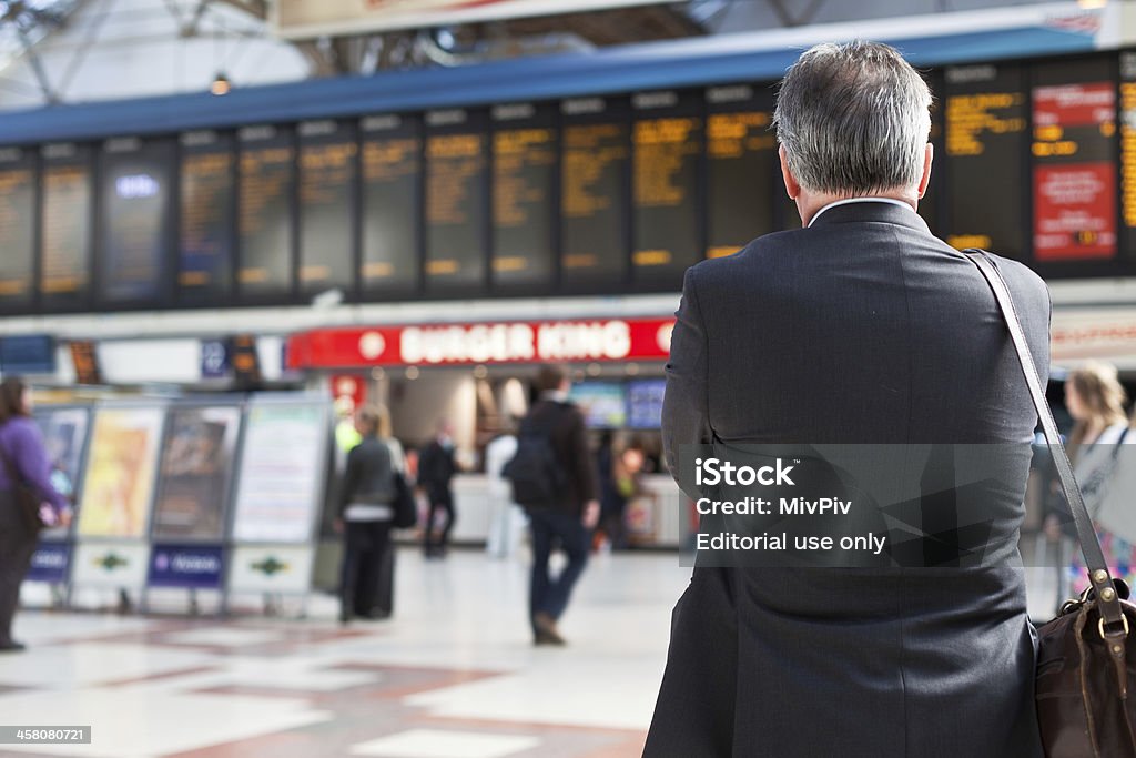 Uomo studia le informazioni scheda a Victoria Station - Foto stock royalty-free di Regno Unito