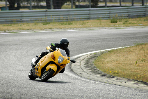 Poland, Poznan - July 5, 2005: A young man riding a motorcycle in the beginner level group, during the course of improving driving skills with motorcycle on the race track in Poznan. 