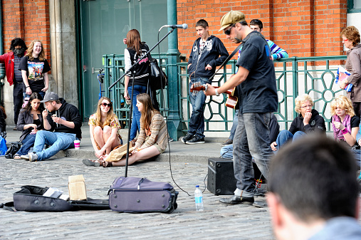 London, United Kingdom - May 1, 2011: A street musician and his audience on Covent Garden square. The area around Covent Garden Market is well-known for its artistic street performers.