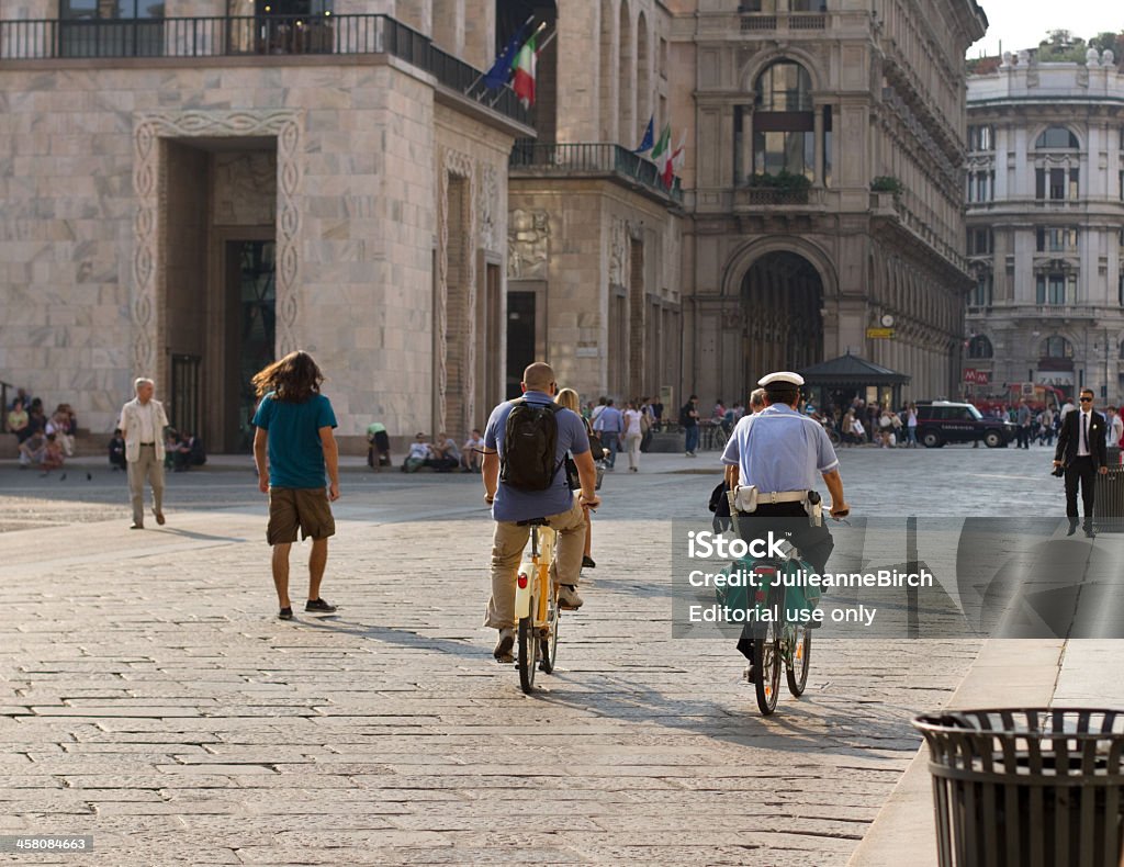 People in Piazza del Duomo Milan, Italy - September 29, 2011: Policeman cycling and a tourist on a yellow bike-Mi (city bike renting system) along with other people walking through the Piazza del Duomo, Milan. Milan Stock Photo