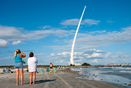 Cocoa Beach, Florida, USA - December 20, 2007: A rocket launches from Cape Canaveral as people watch from the beach at Jetty Park in Cocoa Beach, just to the south of the launch site. The rocket is a Delta II and carries a Global Positioning System satellite designed by Lockheed Martin.