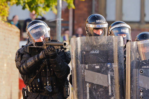 polizist ziele aep (gummigeschoss) pistole auf rioters - bereitschaftspolizist stock-fotos und bilder