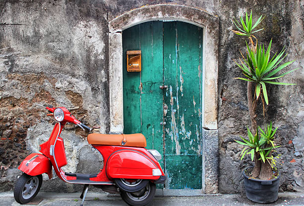 Red scooter "Santa Maria La Scala, Sicily, Italy - April 26, 2010: Red italian classic scooter Vespa near to the old green door." used motorcycle parts stock pictures, royalty-free photos & images