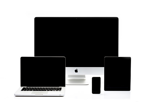 Kampen, The Netherlands - August 20, 2013: Studio shot of a Apple iMac desktop computer, Macbook Pro notebook, iPad tablet and iPhone mobile telephone isolated on a white background with a soft reflection in the foreground.