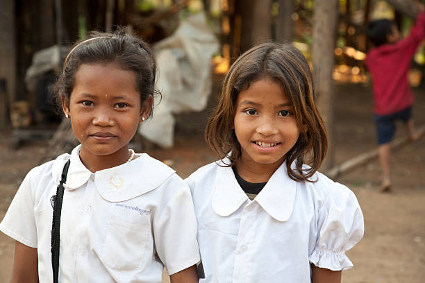 smiling girl students, Cambodia "Kom Pong Pluke, Siem Reap, Cambodia - February 3, 2011:The portrait of  two local smiling girl students  wearing school uniforms.  Kom Pong Pluke is a village which is near Tonle Sap Lake. When rainy season come, the road will be submerged. Houses just like floating on water. The village also is called floating village." cambodian culture stock pictures, royalty-free photos & images