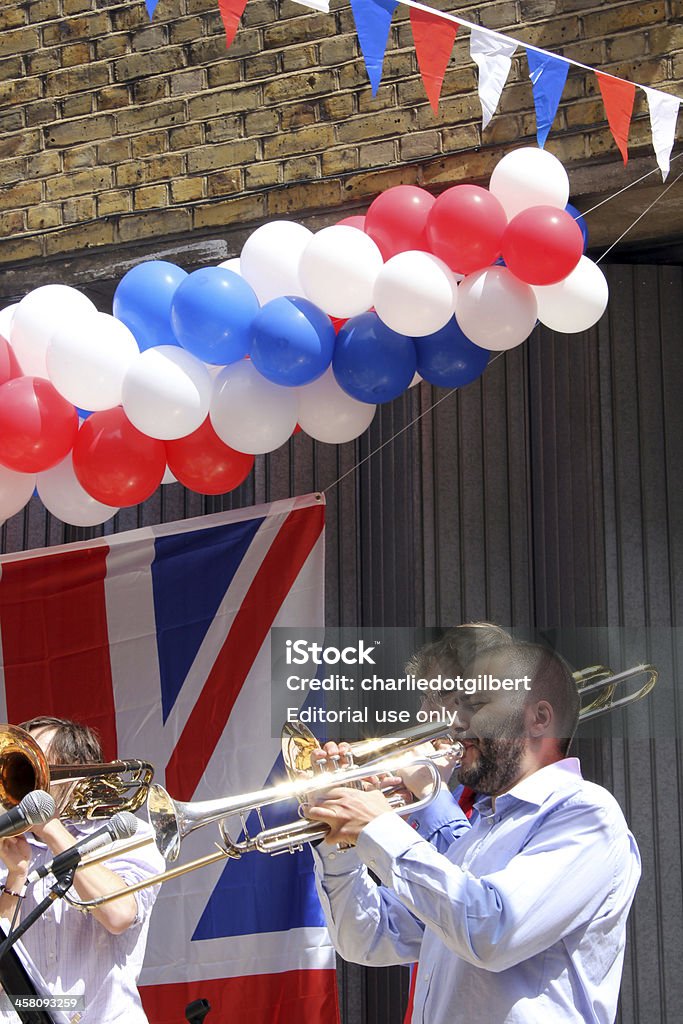 Diamond Jubilee trumpeter, east London "London, England - June 4, 2012: A trumpeter entertains a Folgate Street crowd outside The Poet pub in London's Spitalfields. A street party was held on the road to celebrate Queen Elizabeth II's Diamond Jubilee." British Flag Stock Photo