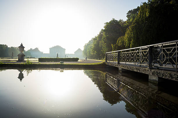 Grounds of Nymphenburg Palace in Munich, Germany "Munich, Germany - August 4, 2013: A pond and bridge is seen on the grounds of Nymphenburg Palace during the morning time. The palace, constructed from 1664-1675, is in the Baroque style and was used as the summer residence for the rules of Bavaria." editorial architecture famous place local landmark stock pictures, royalty-free photos & images