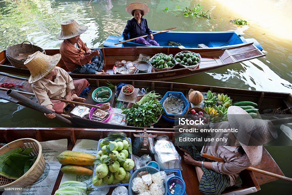 Fruit vendors at Damnoen Saduak Floating Market, Thailand. Ratchaburi Province, Thailand - March 21, 2011: Fuit vendors sell their product at the well-known tourist destination of Damnoen Saduk floating market in Ratchaburi Province. This famous market becomes a hive of colourful activity in the mornings. Floating Market Stock Photo