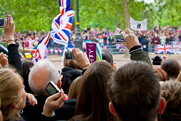 View Of Mounted Police, British Flag Waving And People Looking Around, Taking Picture, Watching British Infantry Regiments Performing Traditional Trooping The Colour Parade During Queen Elizabeth ii Of England Official Birthday Ceremony Outside Of Buckingham Palace In Westminster London England Europe
