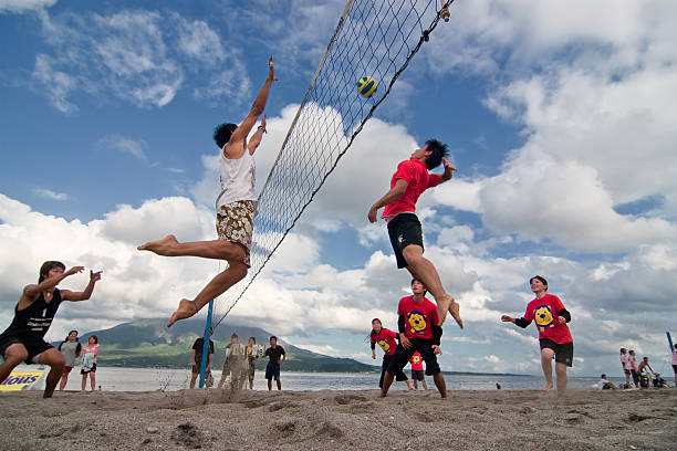 Male  player jumps to spike at  a beach volleyball competition stock photo