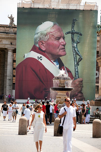 Pope John Paul II in St.Peter's Square Roma Italy "Vatican City, Vatican City State- July 10,2011:Tourists walking  in St. Peter\'s Square in front of the manifest with the face of Pope John Paul II" pope john paul ii stock pictures, royalty-free photos & images