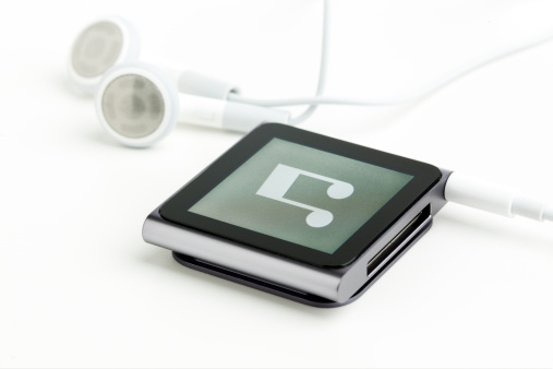 Ratingen, Germany - July 13, 2011: The new Apple iPod Nano 6th generation with multi-touch screen in graphite finish with earphones on white background.