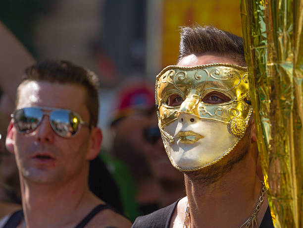 Man with a golden Mask "Stuttgart, Germany - July 27th, 2013 - Man wearing a golden Mask participates at the Christopher Street Day (CSD) parade in Stuttgart in July 2013." gay man men sunglasses party stock pictures, royalty-free photos & images