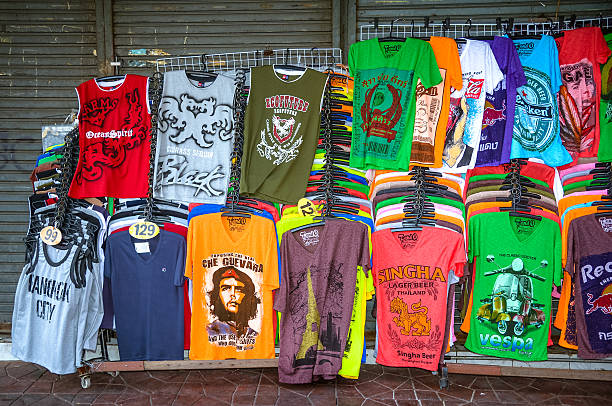 t-shirts for sale in Bangkok "Bangkok, Thailand - July 15, 2013: Many colorful T-shirts for sale on popular Khaosan Road in Bangkok. Khaosan Road is known for its cheap accommodation and street market." graphic t shirt stock pictures, royalty-free photos & images