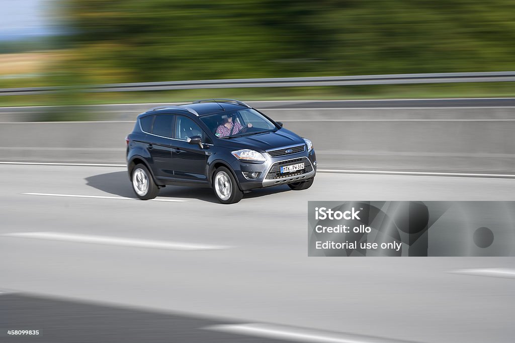 Ford Kuga, high speed "Wallau, Germany - June 28, 2011: A male driver in an accelerating dark-grey Ford Kuga drives on german Autobahn A66 with high speed. Ford Kuga is a compact crossover SUV, produced by Ford starting in 2008. Ford is an american multinational automobile manufacturer based in Detroit and was founded by Henry Ford in 1903. Panned photography, high speed, motion blur" Asphalt Stock Photo