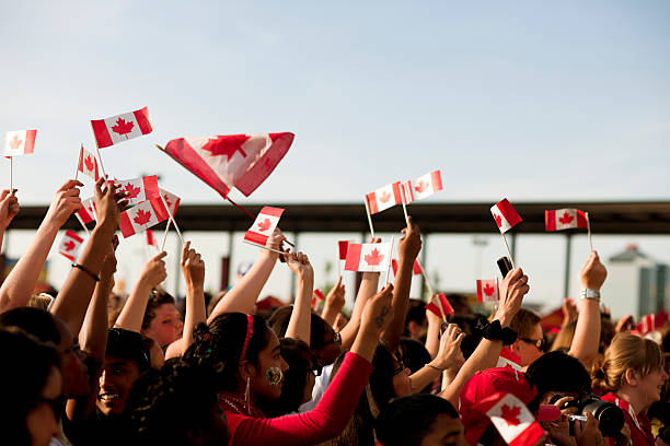 Canadians Waving Flags, Patriotism Mississauga, Canada - July 1, 2011: Peple in large growd waving flags at Mississauga City Centre Canada Day celebration 2011. The celebration included food vendors, an outdoor concert and a fireworks display later in the evening. Mississauga is a suburb located west of Toronto. Mississauga's population is approximately 734,000 people. The city is one of the most ethnically diverse municipalities in Canada. canada day photos stock pictures, royalty-free photos & images