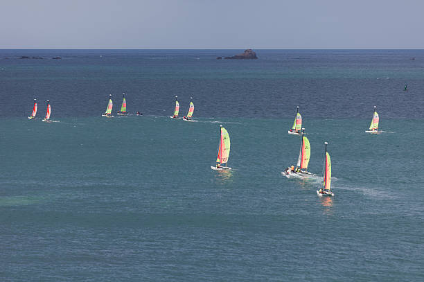 Teenagers learning catamaran sailing in France "Saint-Malo, France - July 6, 2011: Group of teenagers learning catamaran sailing on the coast of Saint-Malo, France. Their Hobie Cat Teddy catamarans are designed for the initiation of youth to the sport. These catamarans are 13 feet long and have a great buoyancy. The coach uses a motor boat." leisure activity french culture sport high angle view stock pictures, royalty-free photos & images