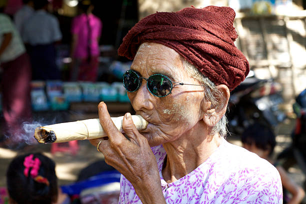 Cheroot Cigar Myanmar Burma "Nyaung-U, Myanmar - October 14, 2011: An unidentified older woman smoking a very large cheroot cigar in Nyaung-U, Myanmar on October 14, 2011." smokers wrinkles stock pictures, royalty-free photos & images