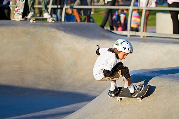 Young Girl Performing In Front Of Crowd At Skateboard Park "Los Angeles, USA - October 1, 2011: Unidentified youth performs skatboarding skills at the Venice Beach Skateboard Park in Los Angeles on October 1, 2011. The park is known locally as the premier skateboarding facility for athletes in tranining." skateboarding stock pictures, royalty-free photos & images