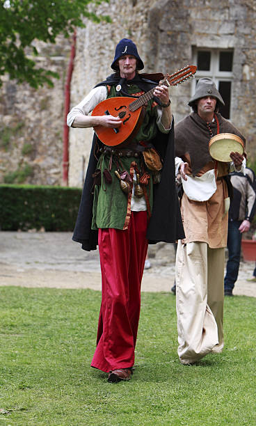 Troubadours on stilts "Nogent le Rotrou,France,May 15th 2010: Medieval troubadours on stilts walking and singing during \""Week-end de L\'ascension-Grand Fete medievale\"" in Nogent de Rotrou, France.This was a historical reenactment festival around the Saint Jean Castle." troubadour stock pictures, royalty-free photos & images