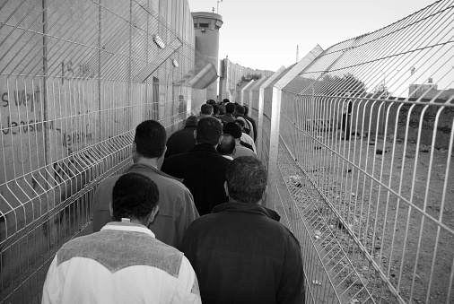 Bethlehem, West Bank (Palestine) - November 12, 2006: Palestinian men wait in line at dawn to cross through the Israeli separation barrier. Some had been waiting for three hours.