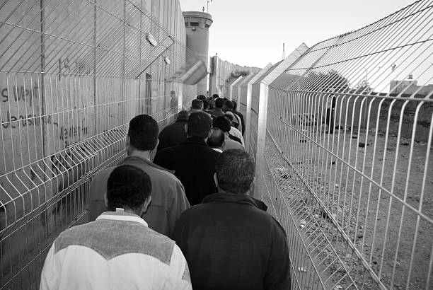 Palestinians waiting in line to cross checkpoint in Bethlehem Bethlehem, West Bank (Palestine) - November 12, 2006: Palestinian men wait in line at dawn to cross through the Israeli separation barrier. Some had been waiting for three hours. west bank stock pictures, royalty-free photos & images