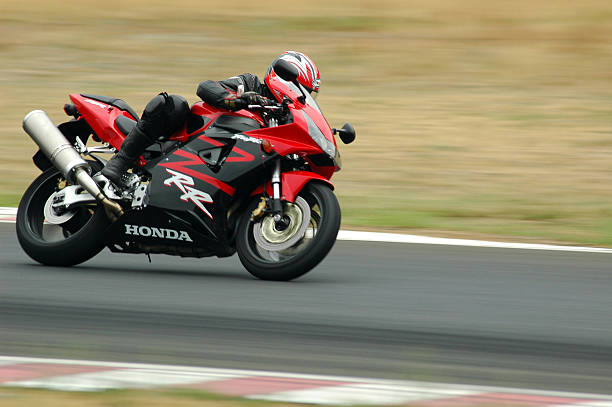 Very fast bike "Poland, Poznan - July 31, 2006: A young woman riding a motorcycle in advanced level group, during the course of improving driving skills with motorcycle on the race track in Poznan." motorcycle racing stock pictures, royalty-free photos & images