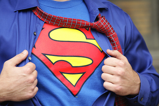 Penfield, New York, USA - October 30, 2009: Young man dressed in a Superman costume pulls off his outer shirt and tie.