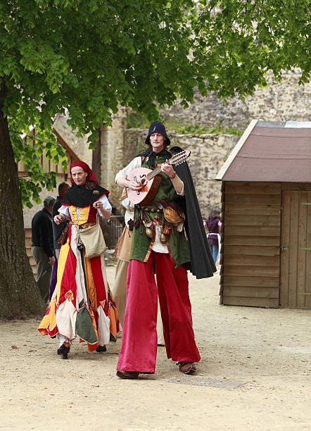 Troubadours on stilts "Nogent le Rotrou,France,May 15th, 2010: Medieval troubadours on stilts walking and singing during Week-end de L\'ascension-Grand Fete medievale in Nogent de Rotrou, France.This was a historical reenactment festival around the Saint Jean Castle." troubadour stock pictures, royalty-free photos & images