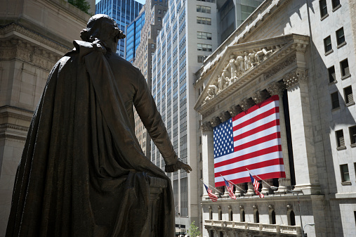 New York, USA - August 7, 2010: Statue of George Washington holds out his hand toward the New York Stock Exchange building. The statue stands in front of a memorial to the building that housed the country's first Congress, Supreme Court, and presidential inauguration.