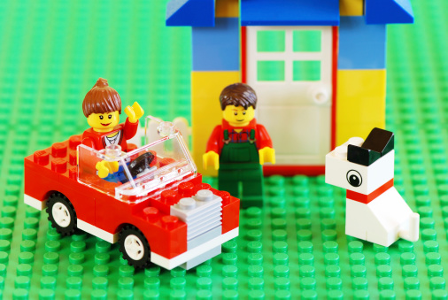 Borgosesia, Italy - October 13, 2011: Happy family with new car, house and dog, focus on the woman. Built with the famous Lego construction block toys. Studio shot.