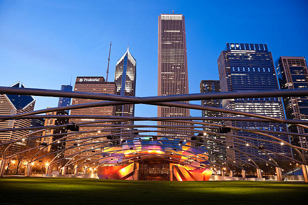 Jay Pritzker Pavilion in Millenium Park and Randolph Avenue Buildings "Chicago; Illinois; USA - March 25, 2012: Jay Pritzker Pavilion in Millenium Park and Randolph Avenue Buildings in Chicago. Seen during spring evening.  The Pavilion was designed by Frank Gehry and opened in 2004." millennium park chicago stock pictures, royalty-free photos & images