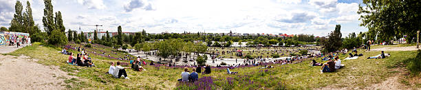 Mauerpark Flee Market Sunday Panorama Berlin, Germany - June 10th, 2012: Wide angle 180 degrees Panoramic view of Mauerpark from its hill top on an early summer sunday, packed with people relaxing on the grass or engaged in various leisure activities. Sundays at Mauerpark are famous for their large flee market along with various shows held by all kinds of performers. mauer park stock pictures, royalty-free photos & images