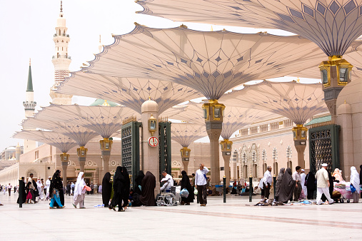 Medina, Saudi Arabia - April 16, 2011: Muslim pilgrims walk in the courtyard of Masjid al-Nabawi ( Prophet's Mosque ). As the final resting place of the Prophet Muhammad, it is considered the second holiest site in Islam by Muslims (the first being the Masjid al-Haram in Mecca).