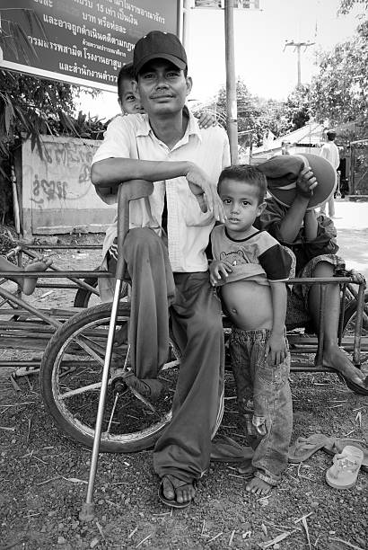 Purulia, West Bengal, India - ‎August ‎26, ‎2017: This playful moment of a village child was found while roaming through the roads of rural Bengal, India. The child is playing with a cycle tyre while his family keeps an eye on him sitting in the background.