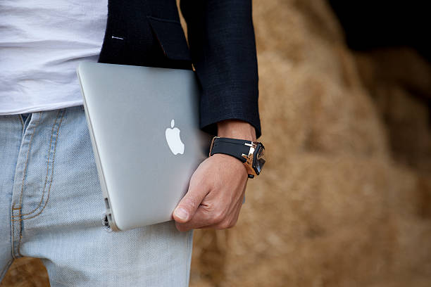 männliche hält macbook air - apple macintosh stock-fotos und bilder