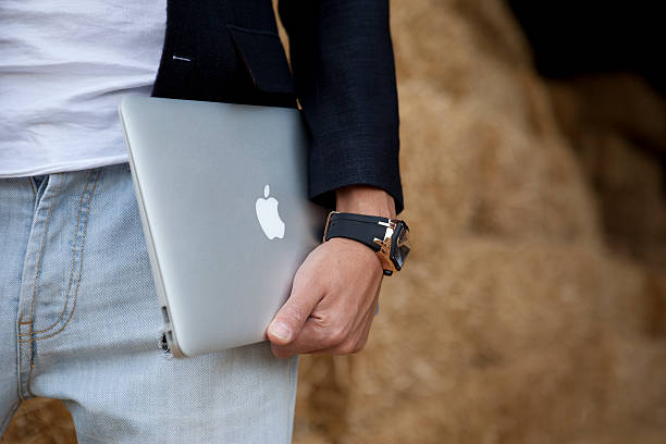 hombre agarra macbook air - avión ultraligero fotografías e imágenes de stock