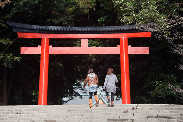 Women walk towards red torii gate at a Japanese shrine stock photo