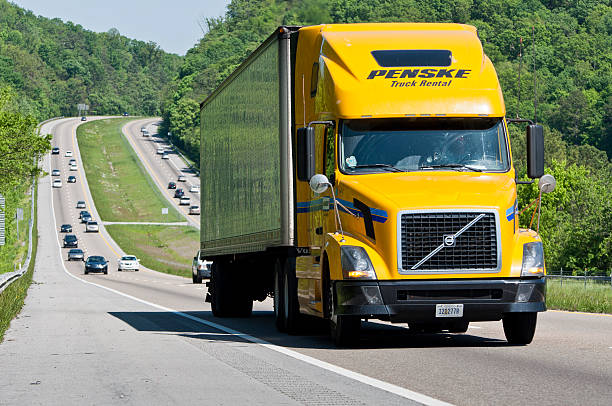 Yellow Penske Rental Truck Climbs Interstate Highway Hill "Eastern Tennessee, USA - May 5, 2011: A yellow Volvo semi truck hauls its load up a hill on Interstate Highway I-40 westbound between Knoxville and Nashville, Tennessee.  In the background are other cars and trucks on the interstate heading in both directions." volvo stock pictures, royalty-free photos & images