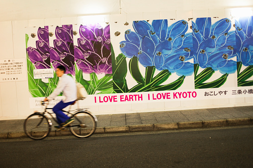 Kyoto, Japan - May 22, 2010: An environmentalist billboard in the street reminds \\'Kyoto Protocol\\' and a man cycling in the street in Kyoto.